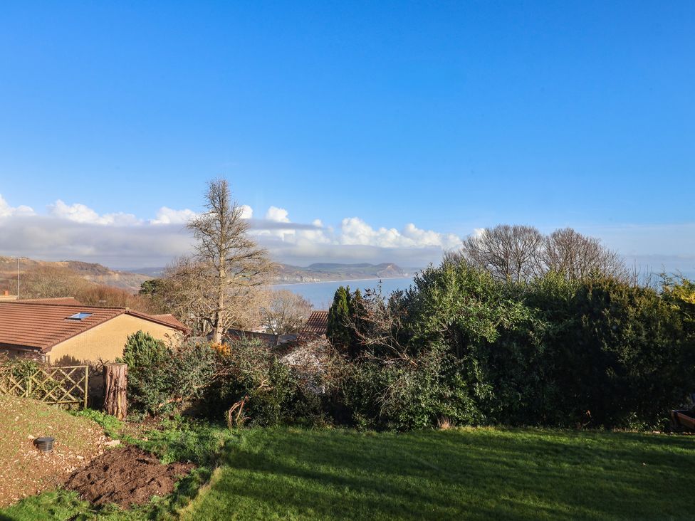 A view of houses and trees with sea in the background at High Cliff Orchard Lyme Regis