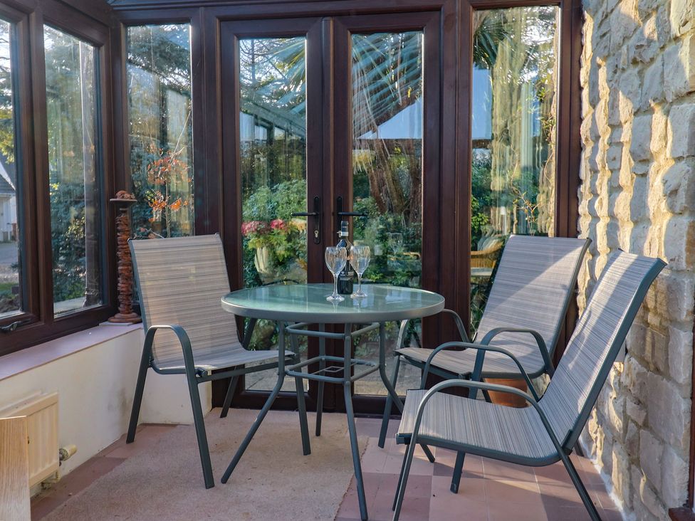 A conservatory with a table and chairs at High Cliff Orchard in Lyme Regis
