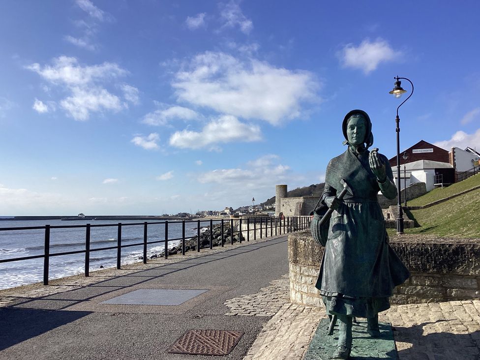 A statue near the sea with a path and buildings at High Cliff Orchard in Lyme Regis