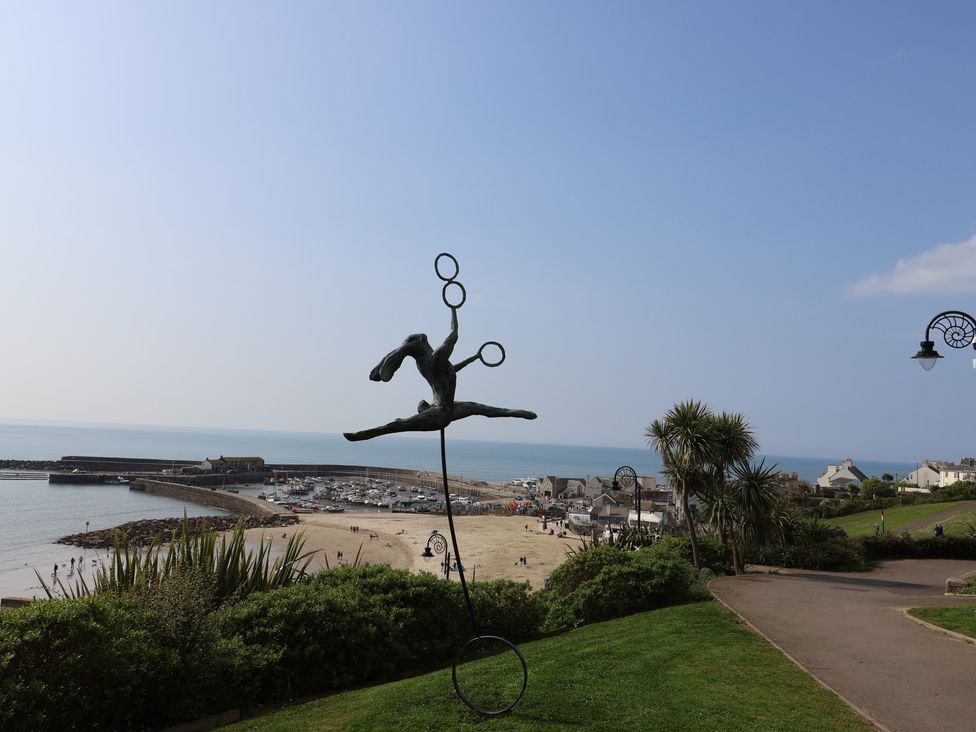 A view of a beach and marina with a sculpture at High Cliff Orchard in Lyme Regis