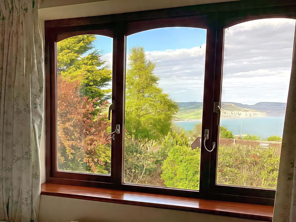 A window showing a view of trees and water at High Cliff Orchard in Lyme Regis