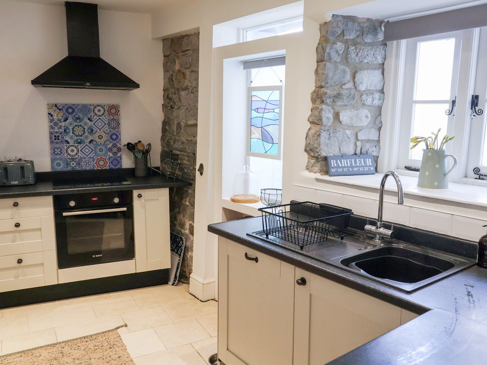 A kitchen with a sink, oven, and window at The Bakehouse in Lyme Regis