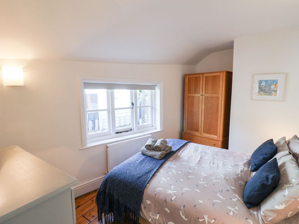 A bedroom with a bed, wardrobe, and window at The Bakehouse in Lyme Regis
