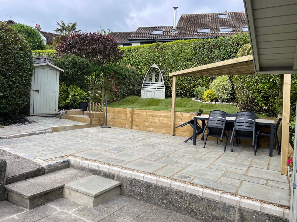 A garden with a patio, table, chairs, and a shed at The Bakehouse in Lyme Regis