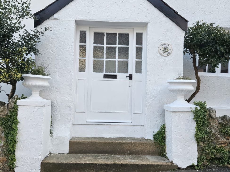 An entrance with a white door and planters at Foxley Cottage in Charmouth