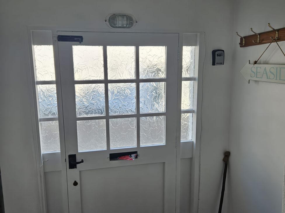 A hallway with a door and a sign at Foxley Cottage in Charmouth