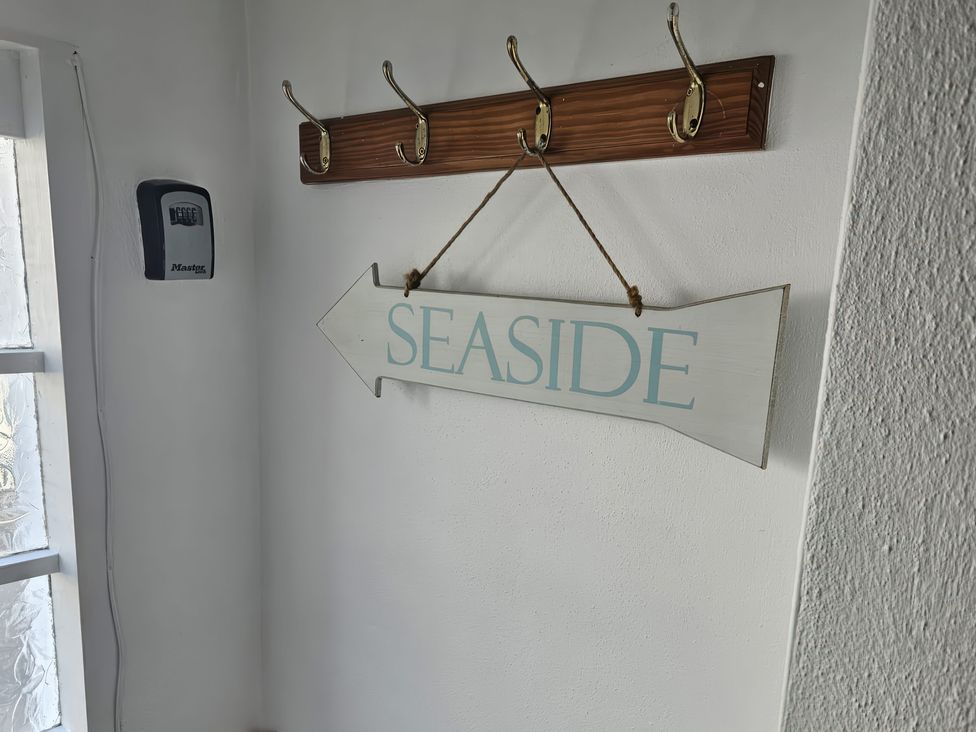 An entryway with coat hooks and a seaside sign at Foxley Cottage in Charmouth