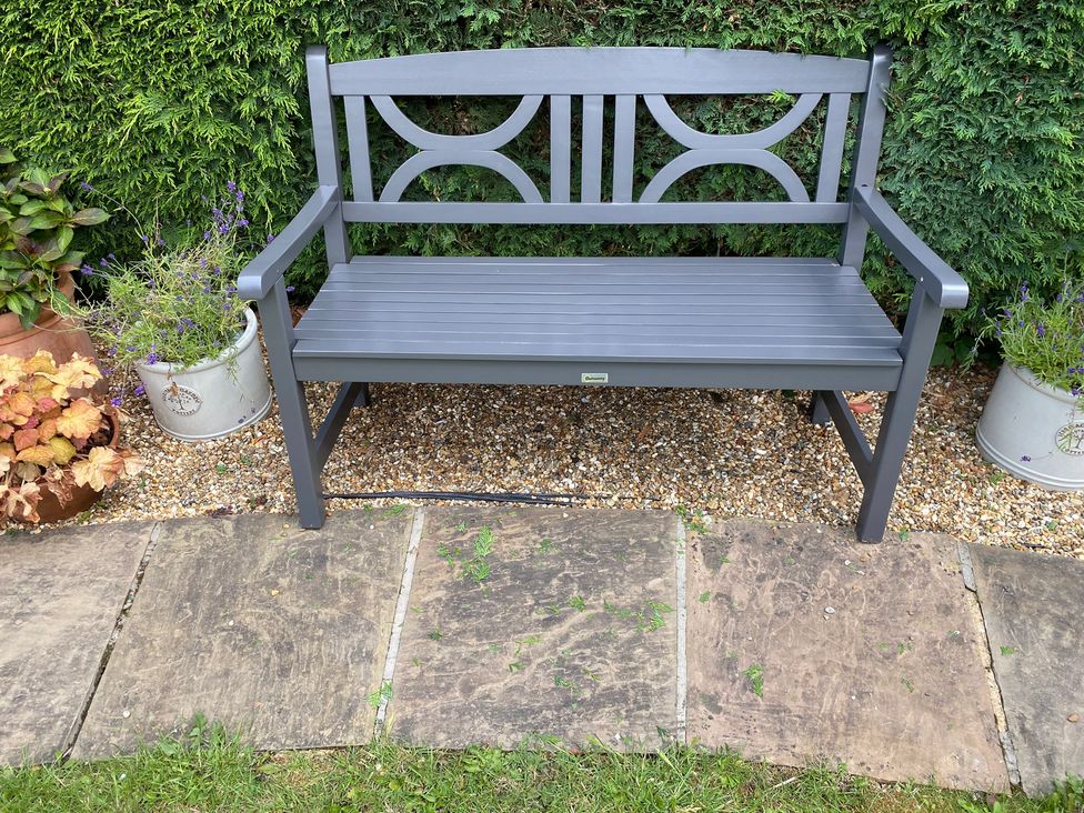 A garden bench on stones with planters at Foxley Cottage Charmouth