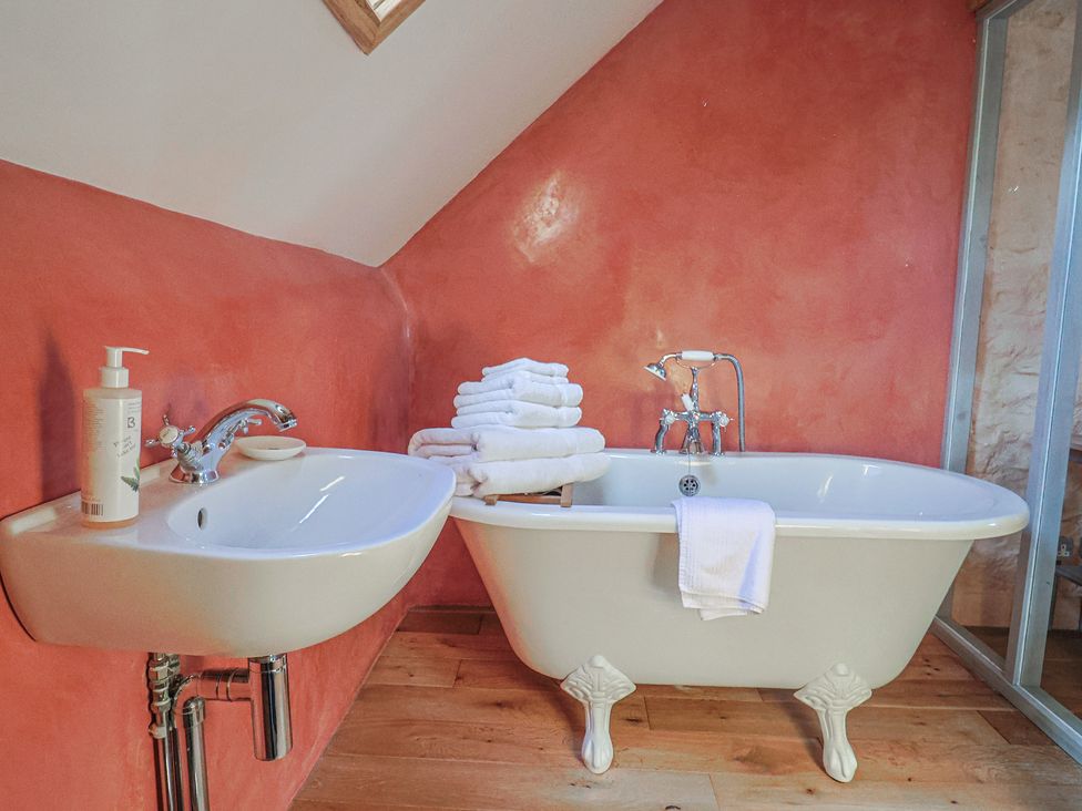A bathroom with a bathtub and washbasin at The Stone Barn in Bridport