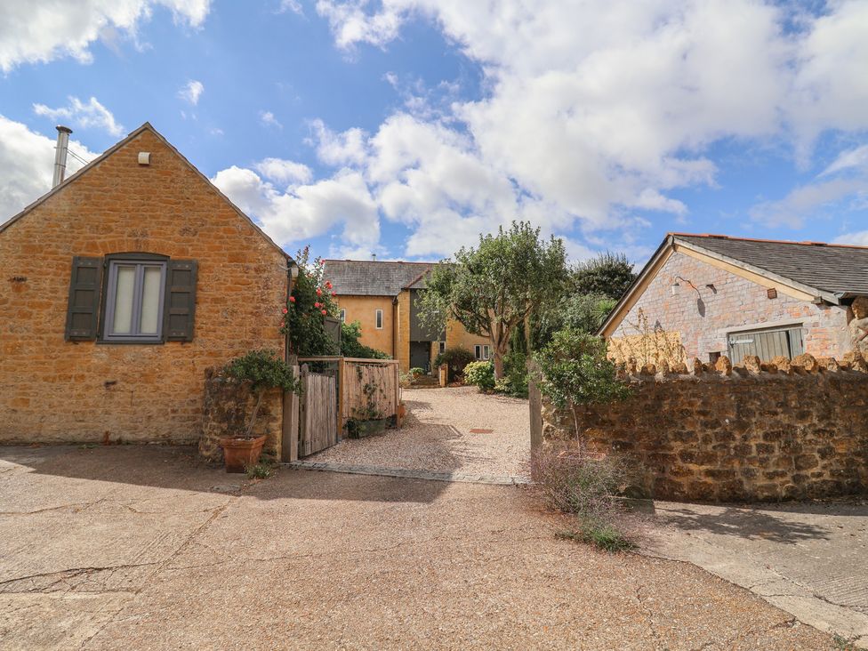 An outdoor view of buildings and trees at The Stone Barn in Bridport