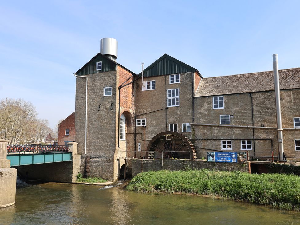 A watermill with a bridge over a river at The Stone Barn in Bridport