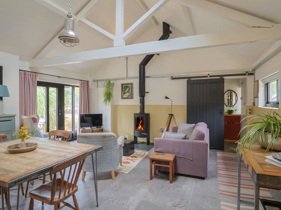 A living room with a table, sofa, and stove at The Dairy in Bridport