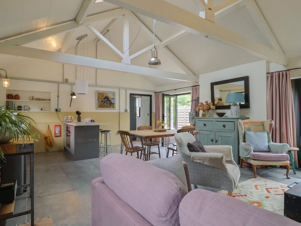 A living room with a sofa, chairs, and kitchen island at The Dairy in Bridport