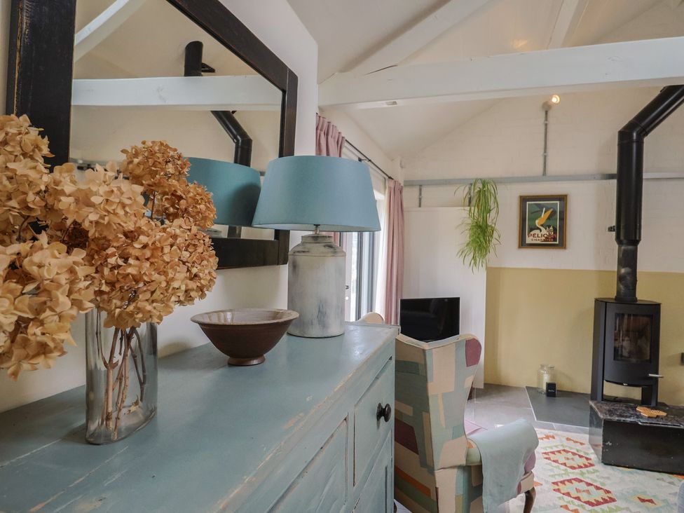 A living room with a mirror, lamp, sofa and stove at The Dairy in Bridport