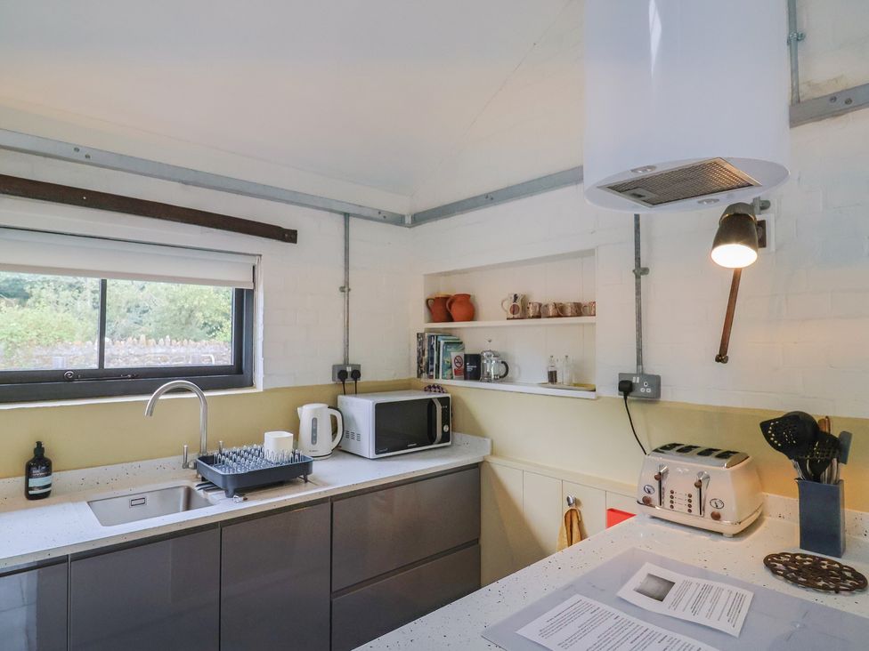 A kitchen with sink, microwave, toaster, and shelves at The Dairy in Bridport
