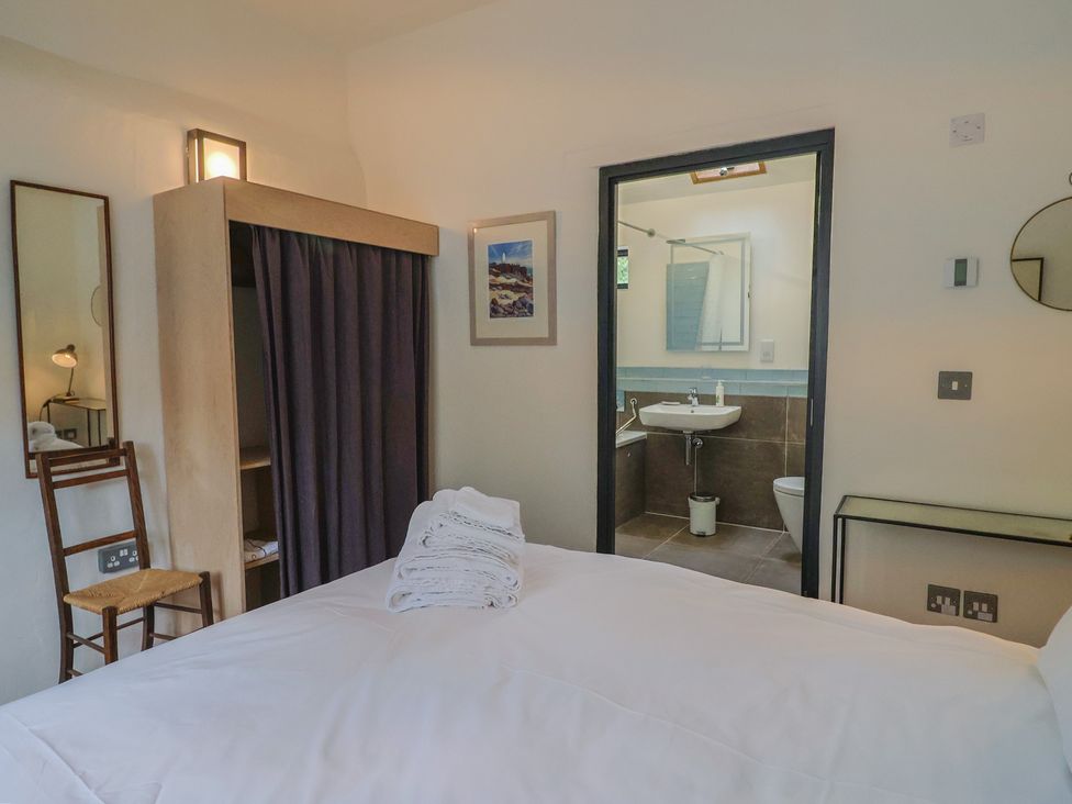 A bedroom with a bed and bathroom access at The Dairy in Bridport