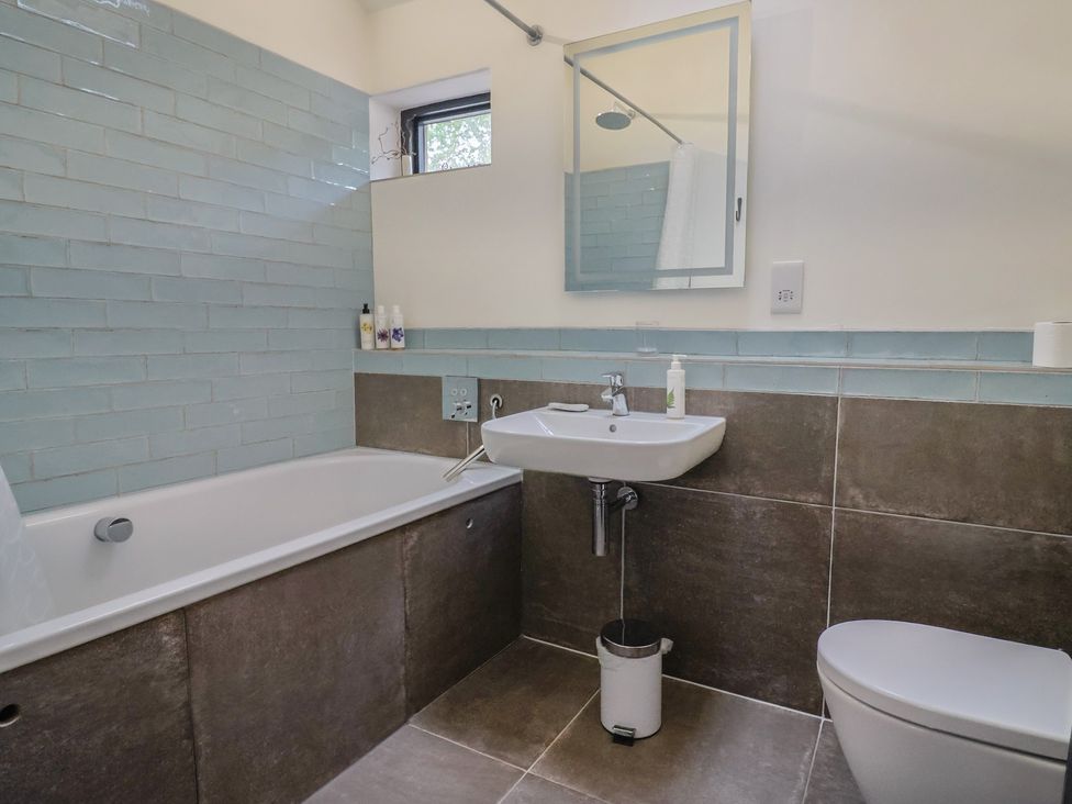A bathroom with a bathtub, sink, and toilet at The Dairy in Bridport