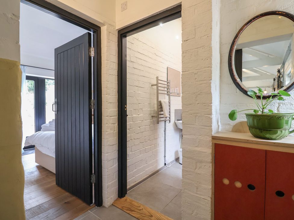 A hallway with a cabinet and doors leading to a bathroom and bedroom at The Dairy Bridport