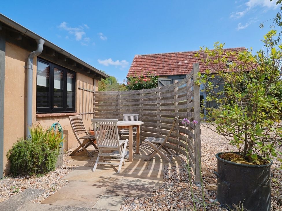 An outdoor area with a table and wooden chairs at The Dairy in Bridport