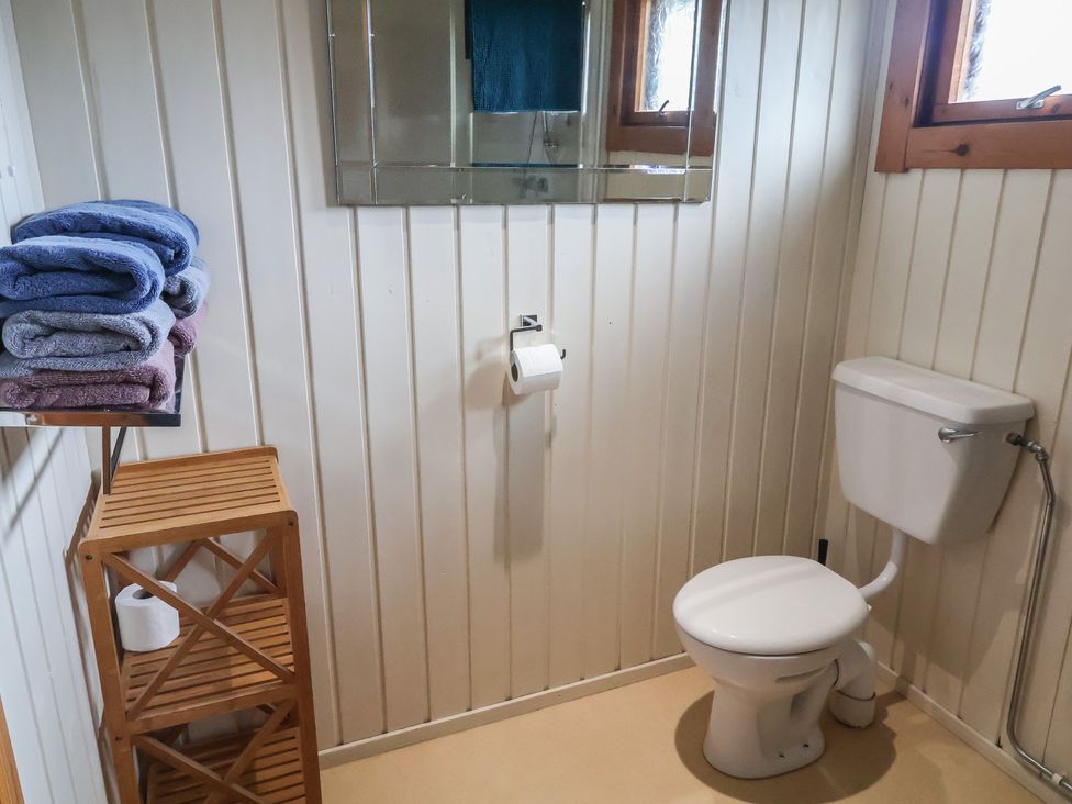 A bathroom with towels on a shelf and a toilet at 10 Pinewood Retreat in Pinewood