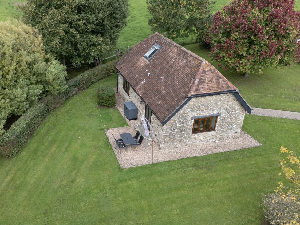 A stone house with patio furniture in a garden at The Cider House in Dalwood