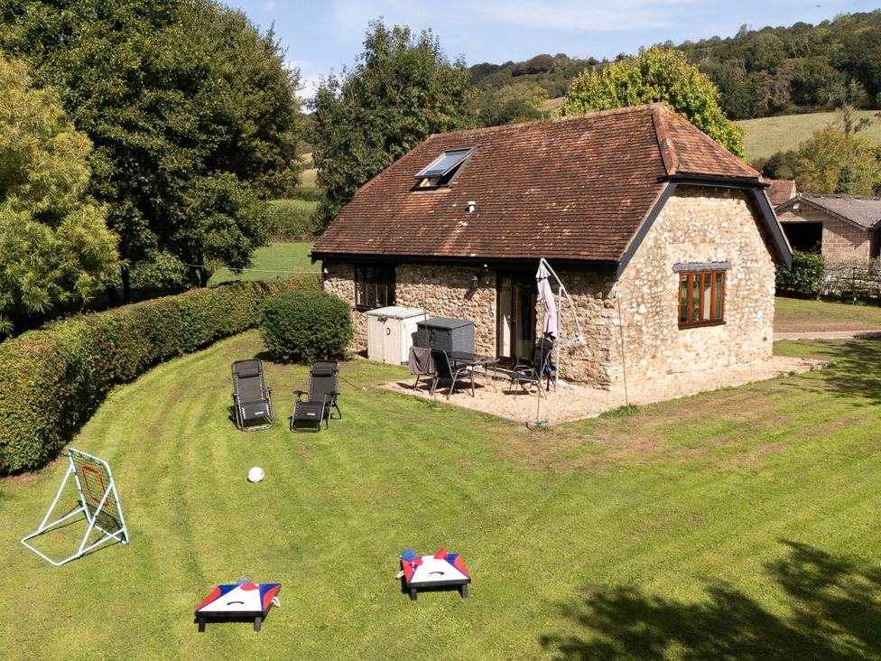 A cottage with a lawn featuring deck chairs and game equipment at The Cider House in Dalwood