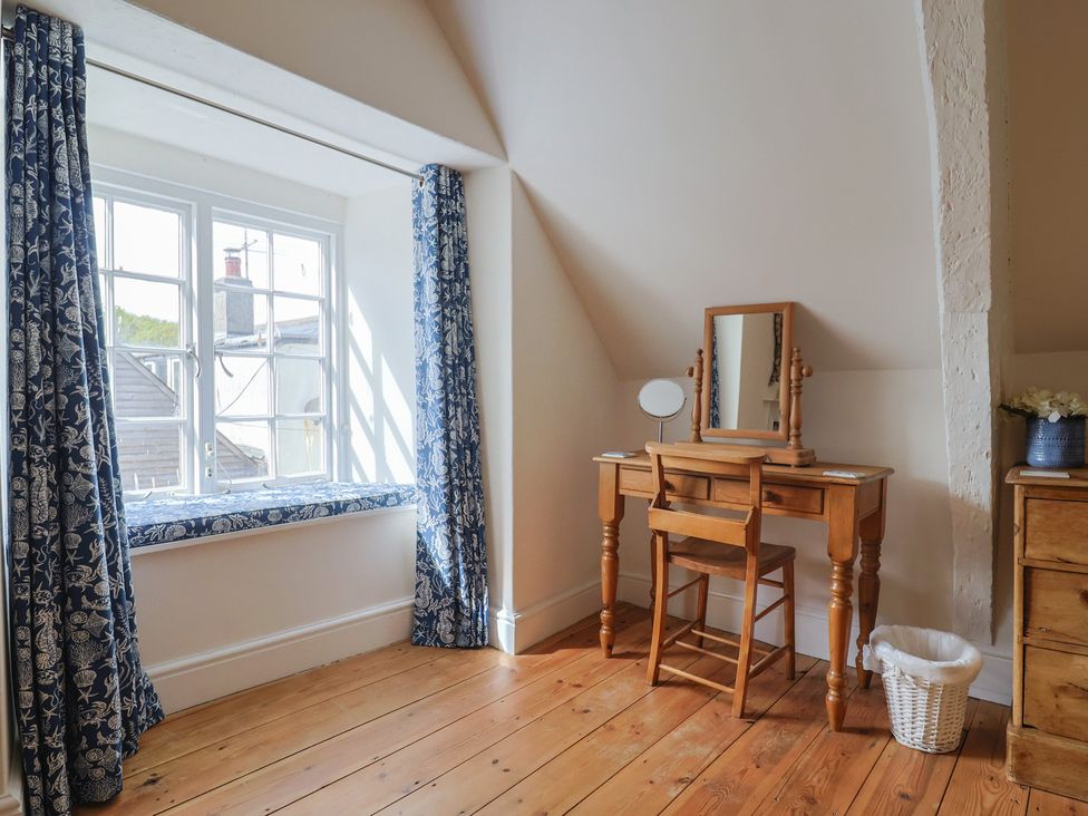 A bedroom with a dresser and window at The Little Rose in Lyme Regis