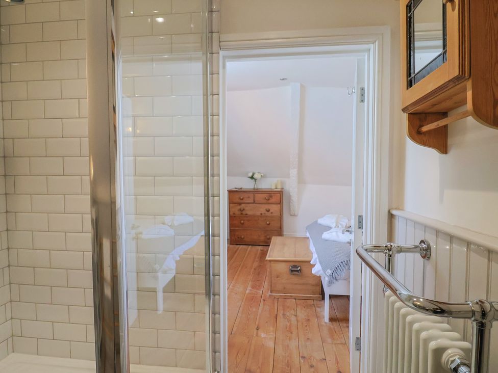 A bathroom with a shower and a view into an adjacent bedroom at The Little Rose in Lyme Regis