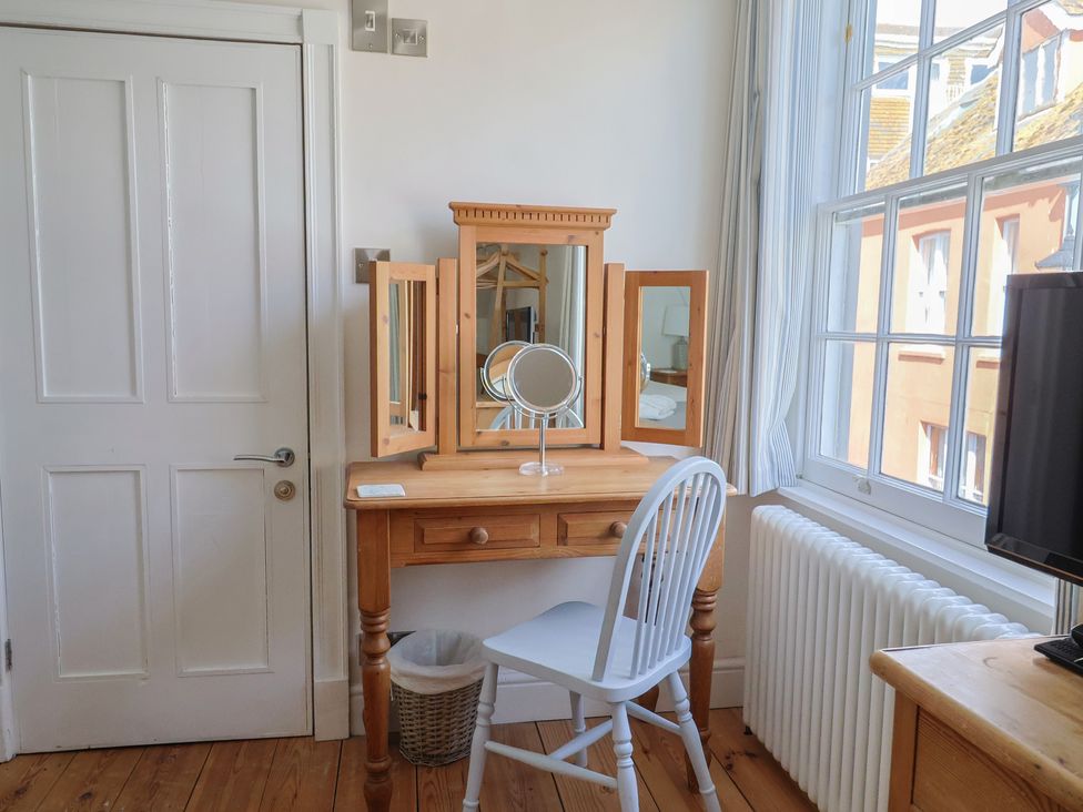 A dressing table with a mirror and chair at The Little Rose in Lyme Regis