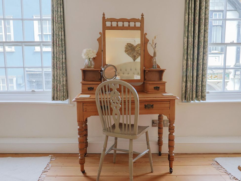 A vanity table with a mirror and a chair at The Little Rose in Lyme Regis