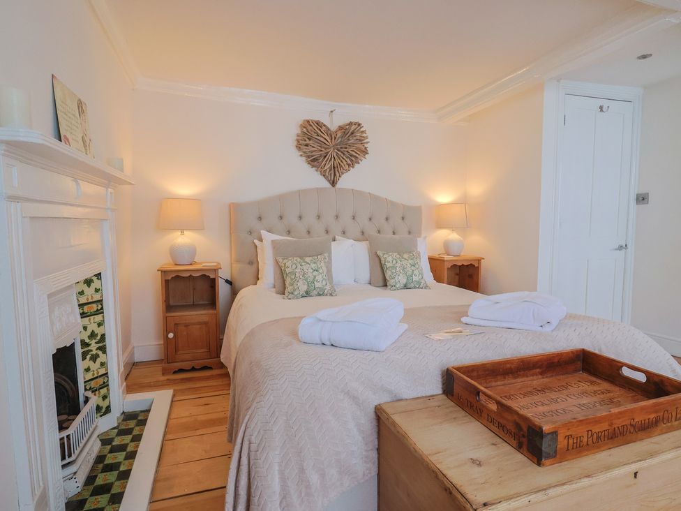 A bedroom with a bed, nightstand, and decorative heart at The Little Rose in Lyme Regis