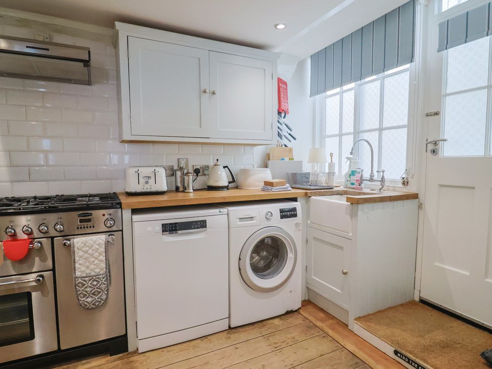 A kitchen with appliances including a stove, dishwasher, washing machine, and sink at The Little Rose in Lyme Regis