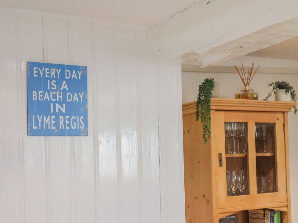 A sign on the wall and a wooden cabinet with glassware at The Little Rose in Lyme Regis