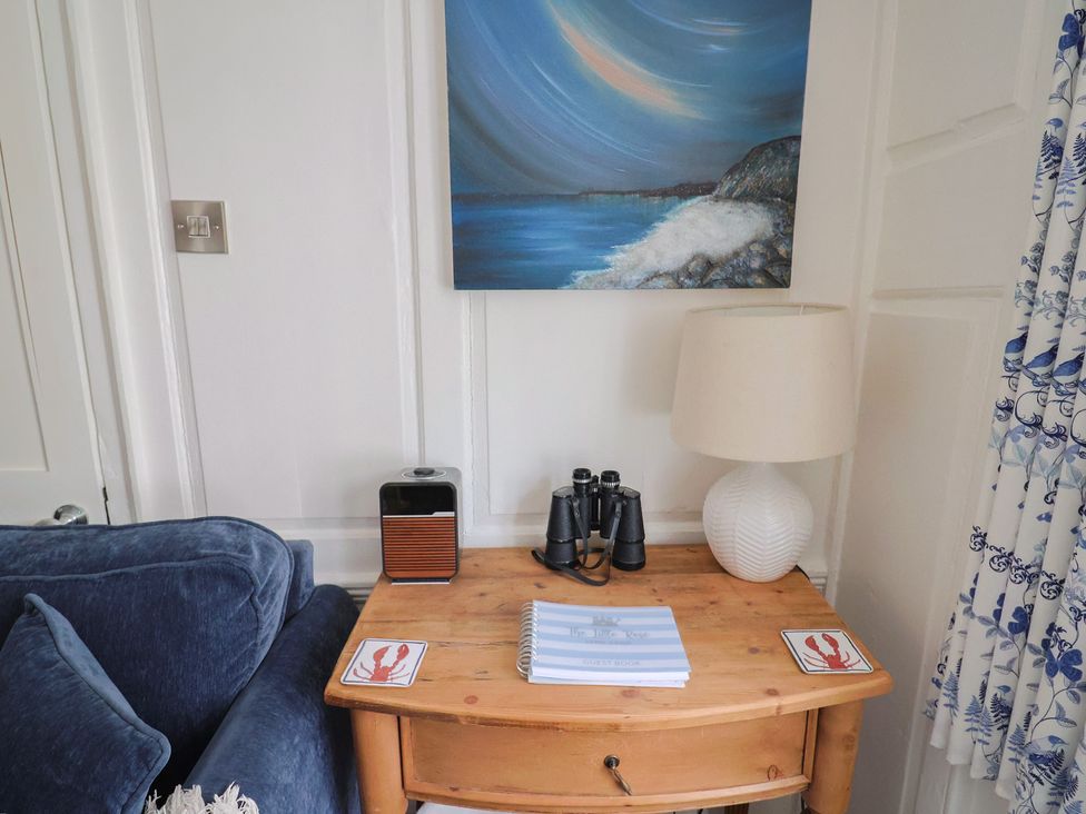 A living room with a couch and table with binoculars at The Little Rose in Lyme Regis