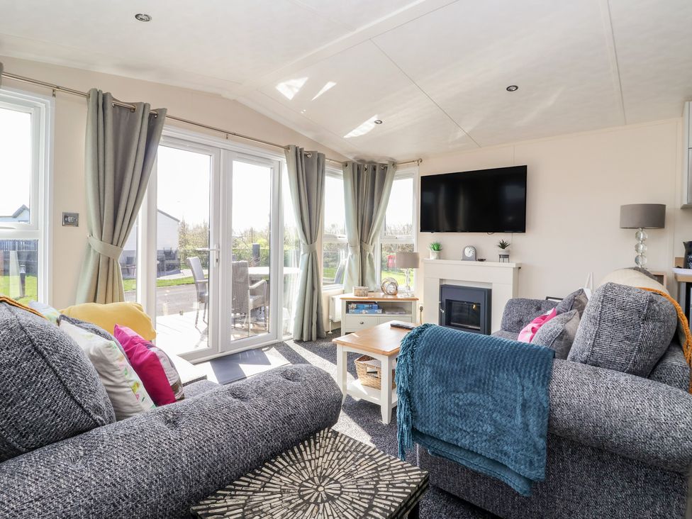 A living room with a television and a sliding door at Away Daze in Carnaby near Bridlington