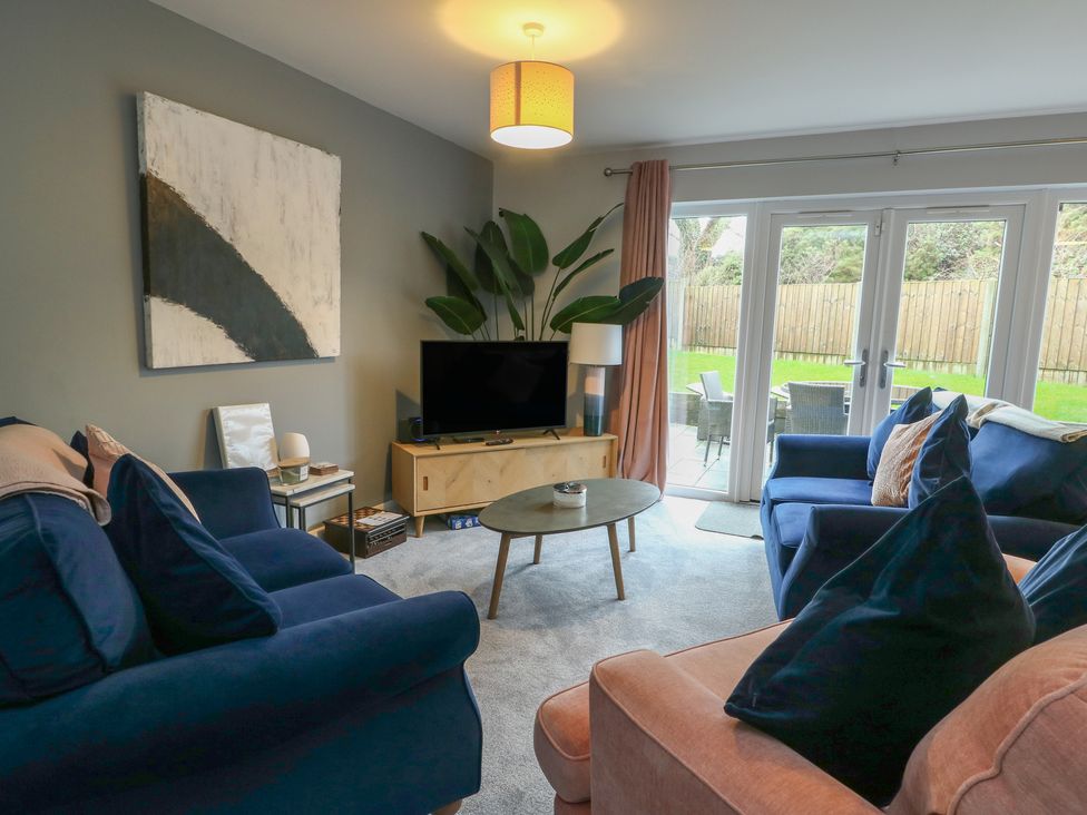 A living room with a television and sliding doors at 11 Parc Delfryn near Benllech