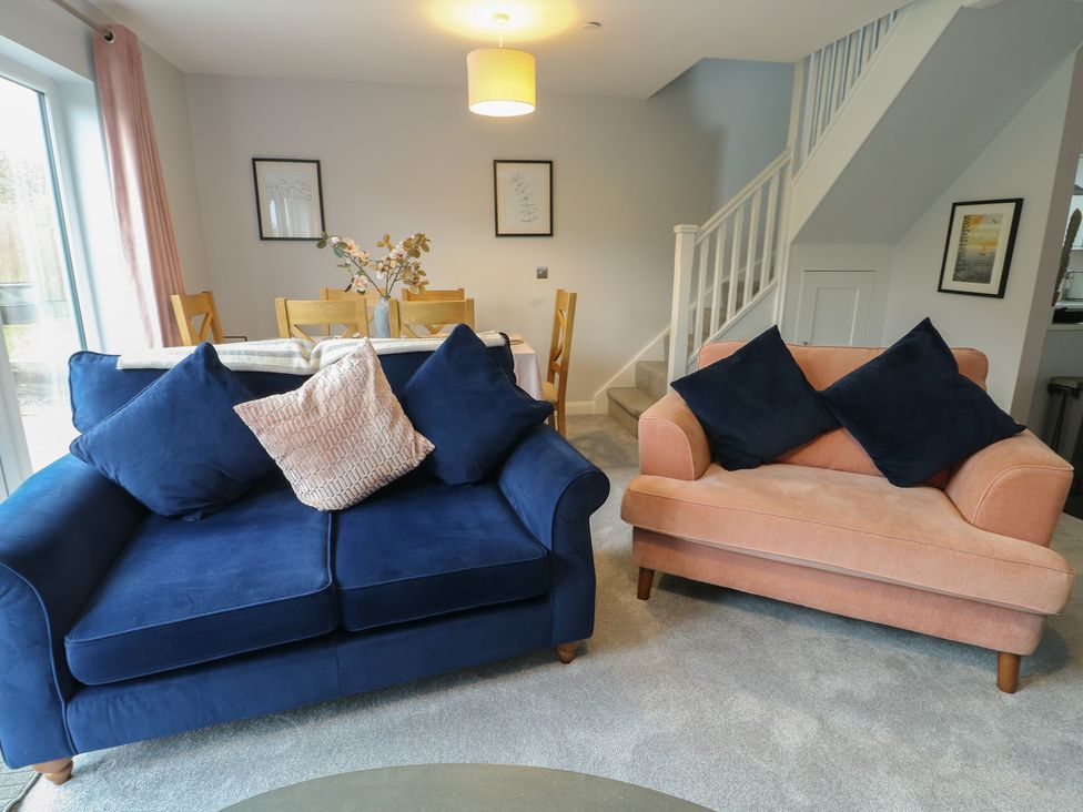 A living room with a blue sofa and a pink armchair at 11 Parc Delfryn Brynteg near Benllech