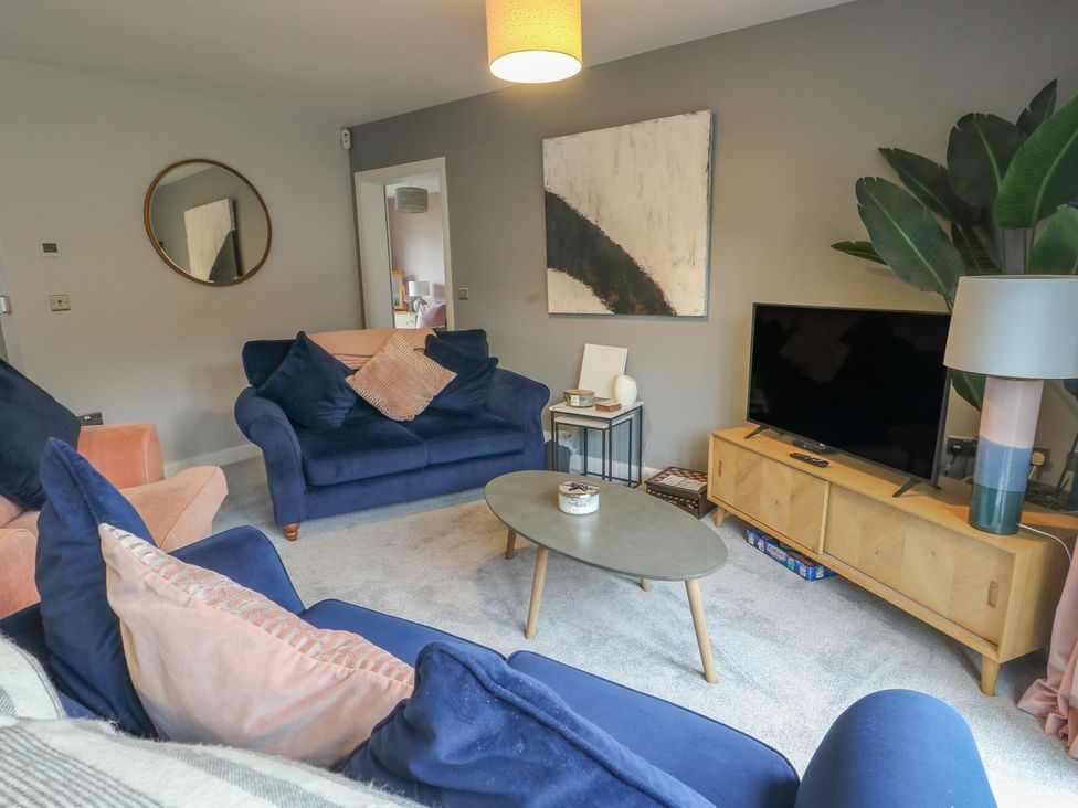 A living room with blue sofas and a coffee table at 11 Parc Delfryn in Brynteg near Benllech