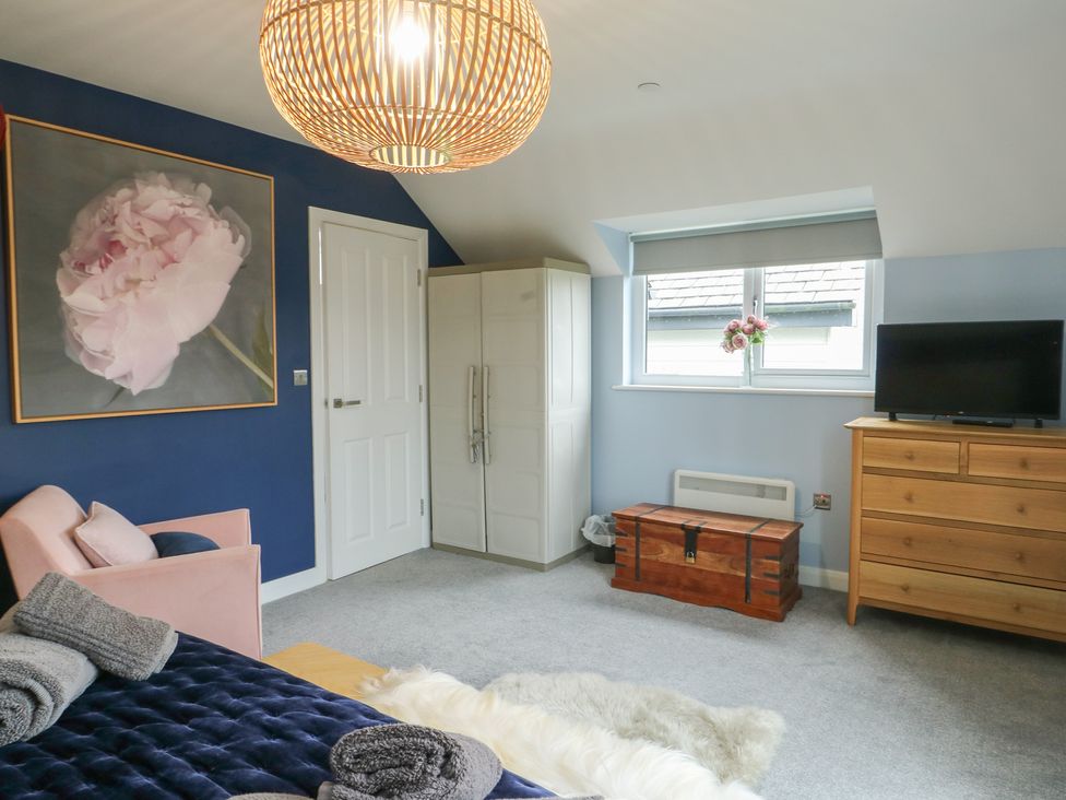 A bedroom with a bed, armchair, and dresser at 11 Parc Delfryn in Brynteg near Benllech