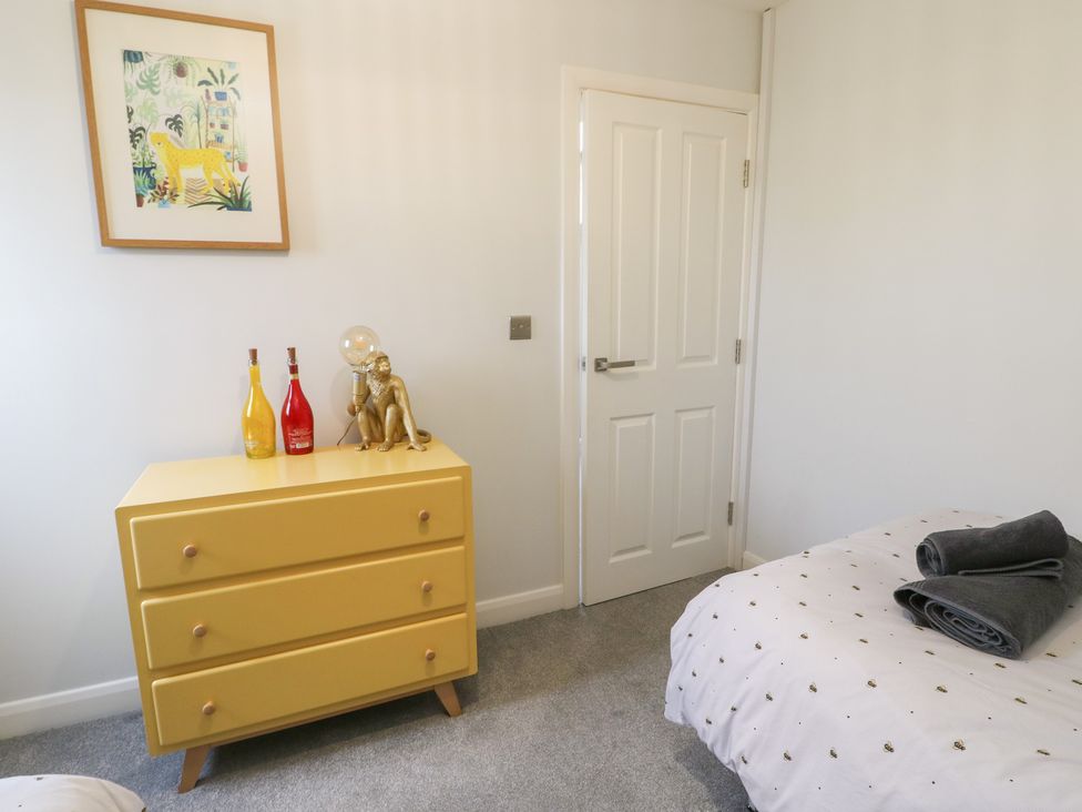 A bedroom with a yellow dresser, decorative items, and a bed at 11 Parc Delfryn Brynteg near Benllech