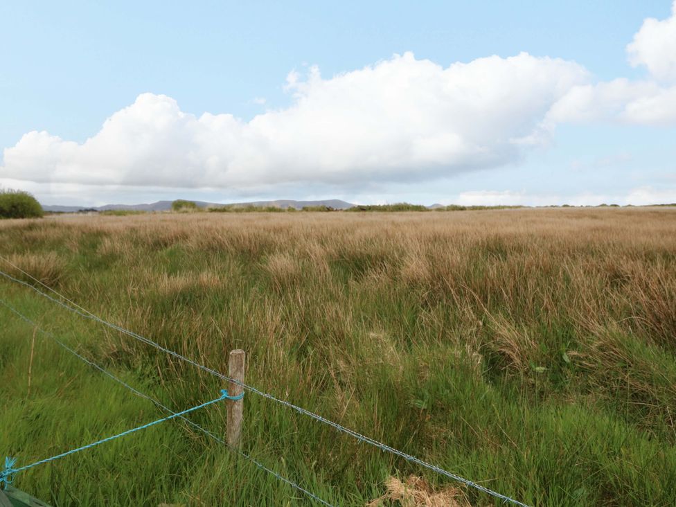 A grassy field with a fence and clouds at Forest View, Ballinskelligs, County Kerry