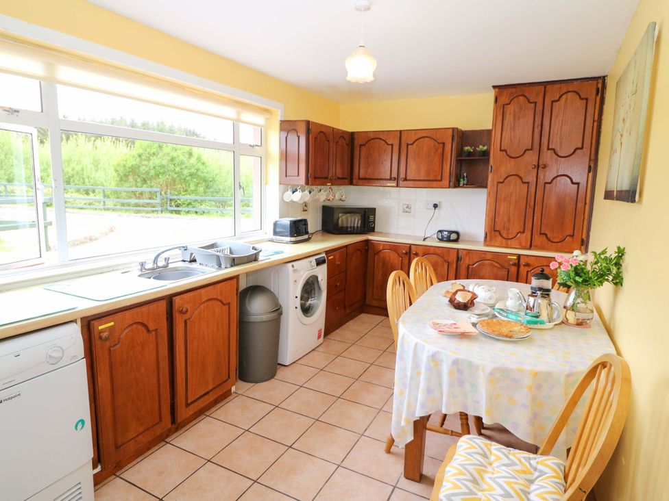 A kitchen with wooden cabinets and a table set for breakfast at Forest View Ballinskelligs County Kerry
