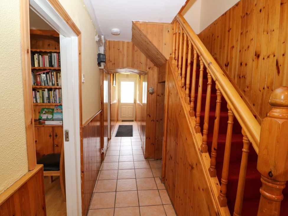 A hallway with a staircase and bookcase at Forest View in Ballinskelligs, County Kerry