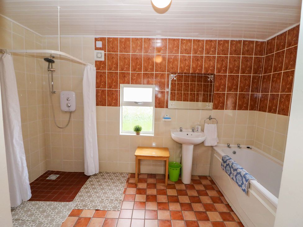 A bathroom with a shower, bathtub, sink, and a mirror at Forest View, Ballinskelligs, County Kerry