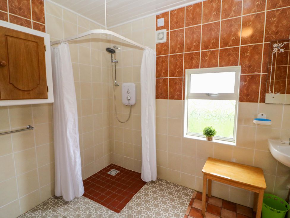 A bathroom with a shower, sink and wooden stool at Forest View in Ballinskelligs, County Kerry