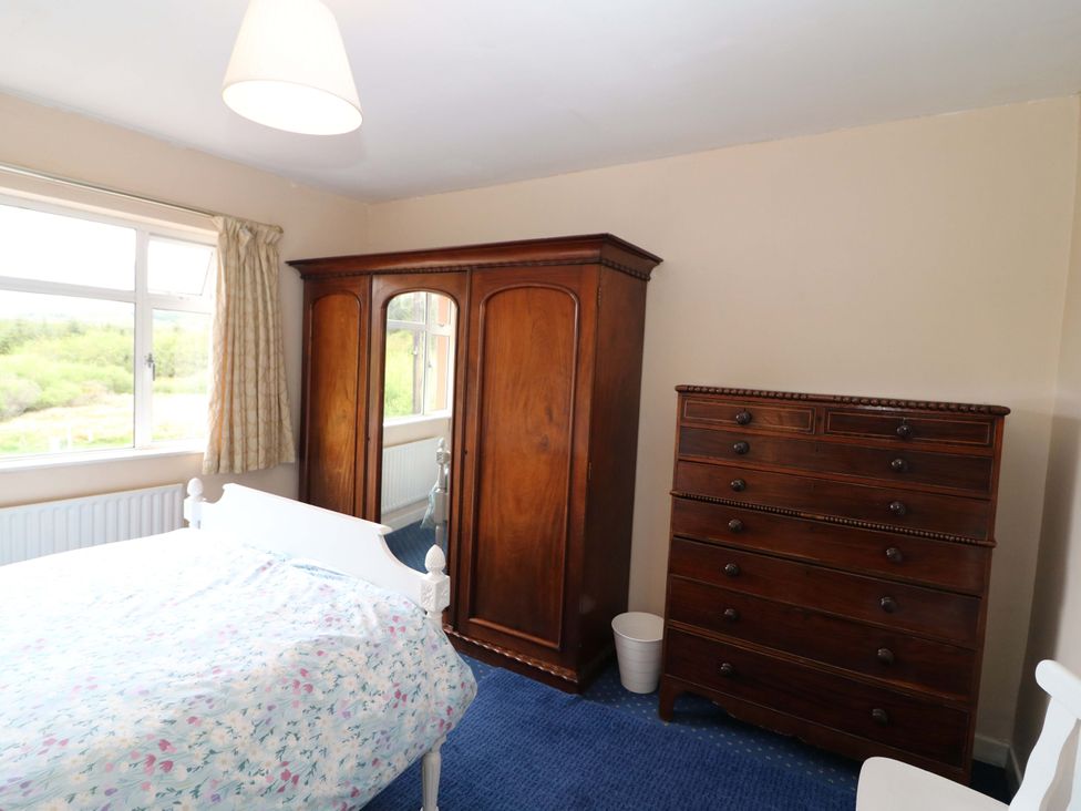 A bedroom with a bed and wooden furniture at Forest View in Ballinskelligs, County Kerry