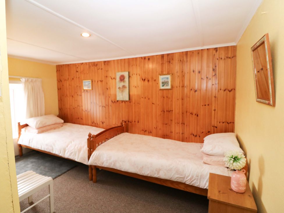 A bedroom with two beds and a table at Forest View, Ballinskelligs, County Kerry