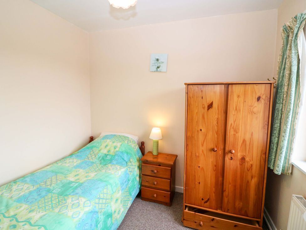 A bedroom with a bed, wardrobe, and lamp at Forest View in Ballinskelligs, County Kerry
