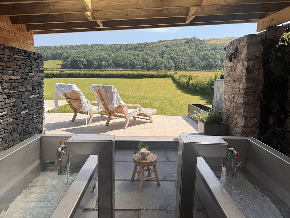 An outdoor area with spa tubs and wooden chairs at Low Longlands, Cartmel
