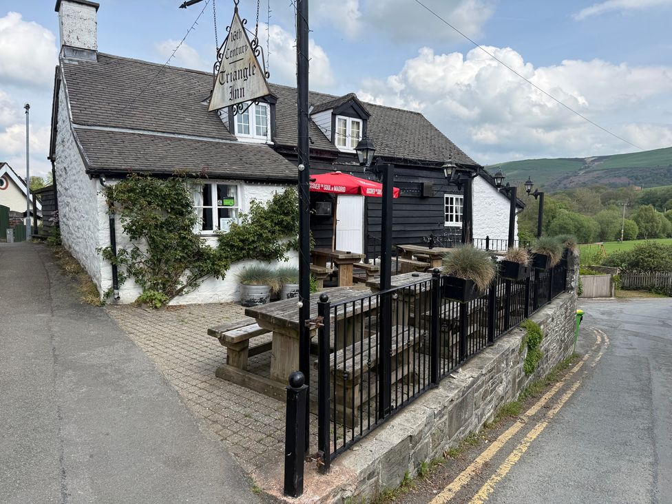 An outdoor area of a pub with tables and benches at Triangle Inn Coachouse Rhayader
